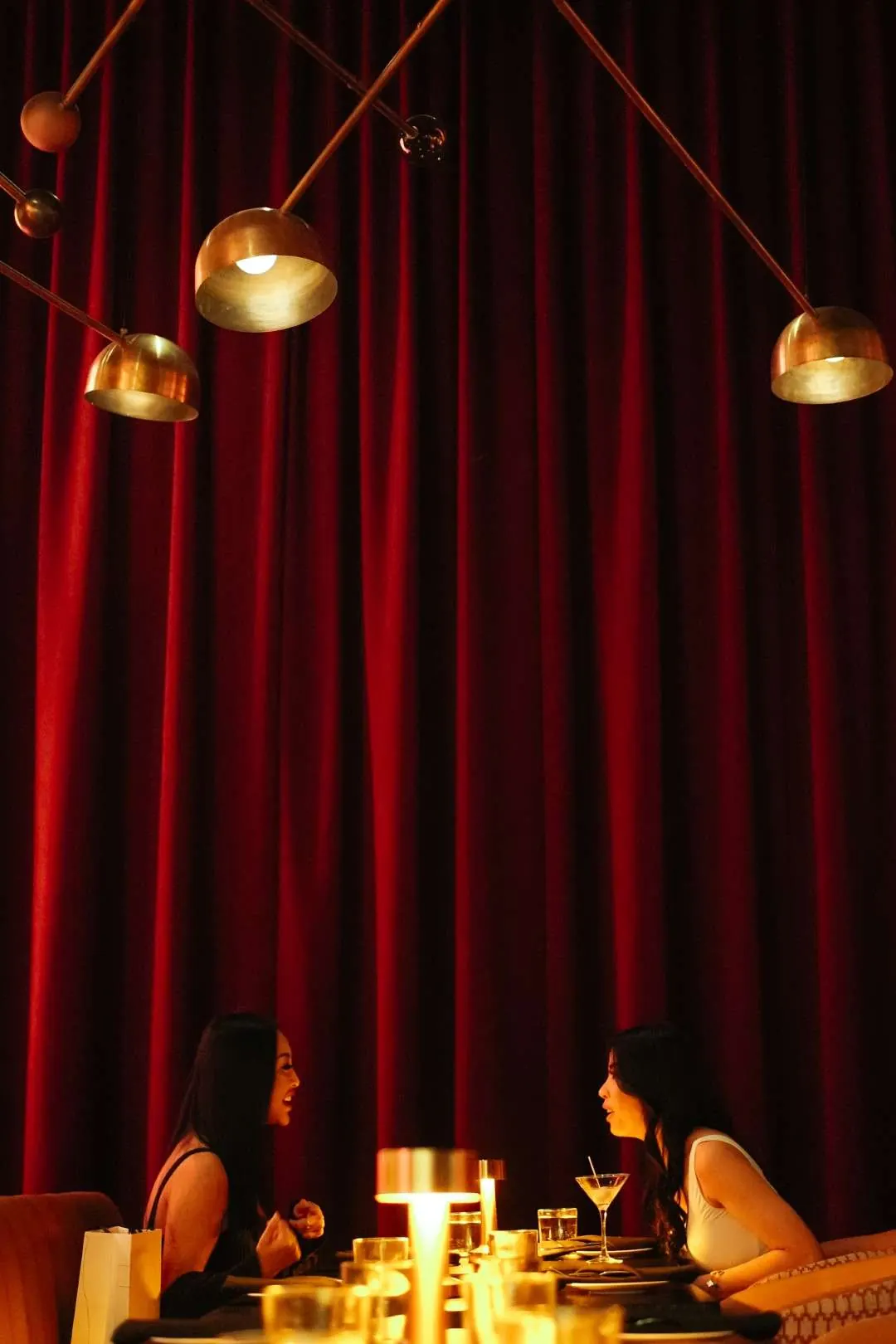 Candlelit table for two beneath red velvet curtains