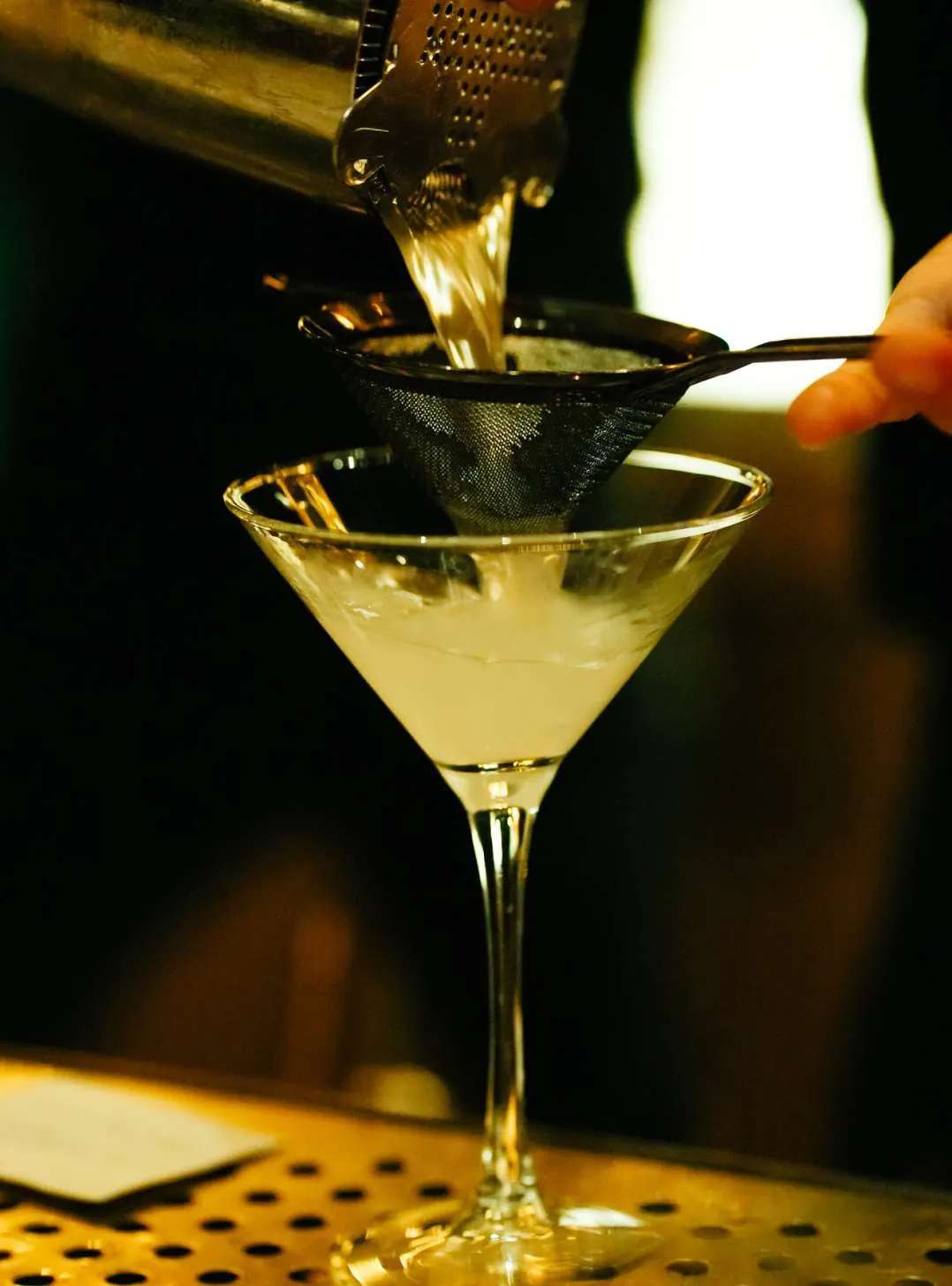 Martini being strained into a chilled glass at the bar