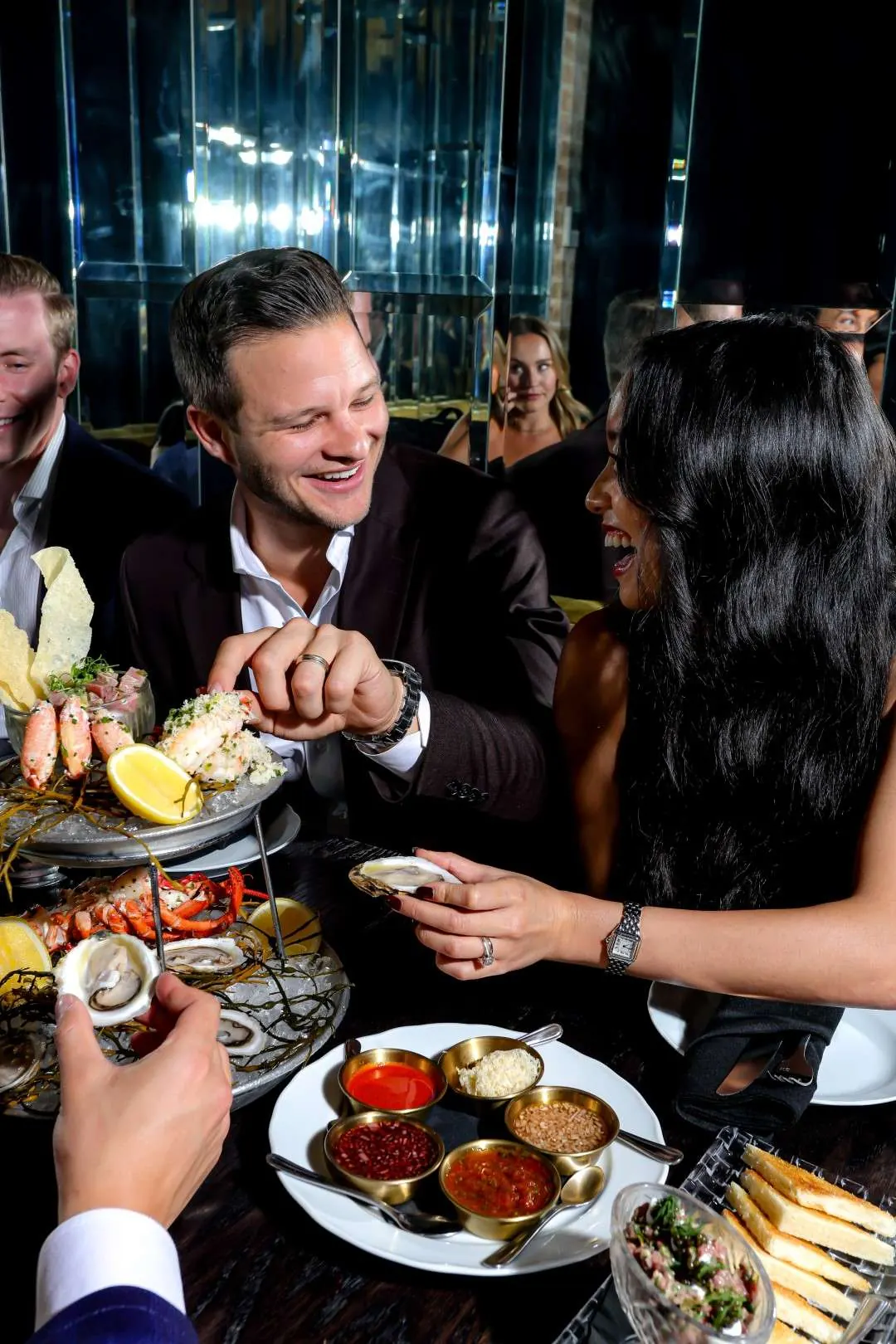 Guests laughing over oysters and a seafood tower at Maxime’s