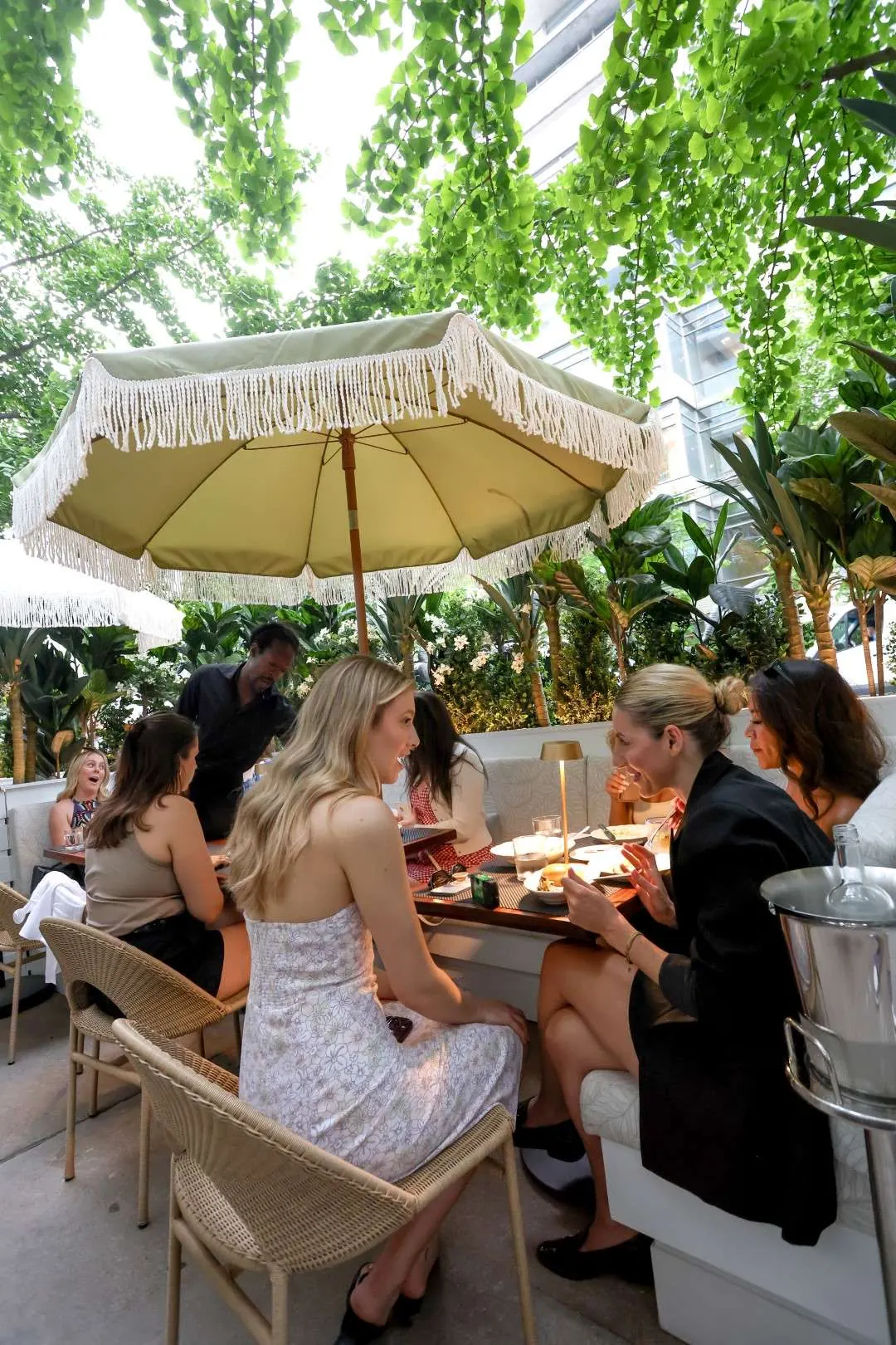 Guests dining on the leafy patio at Maxime’s