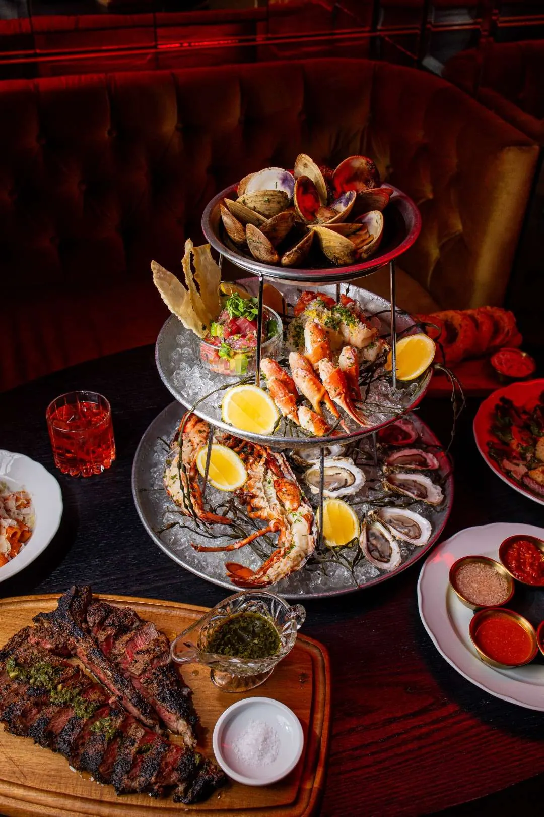 Seafood tower with oysters, shrimp and lobster beside a steak