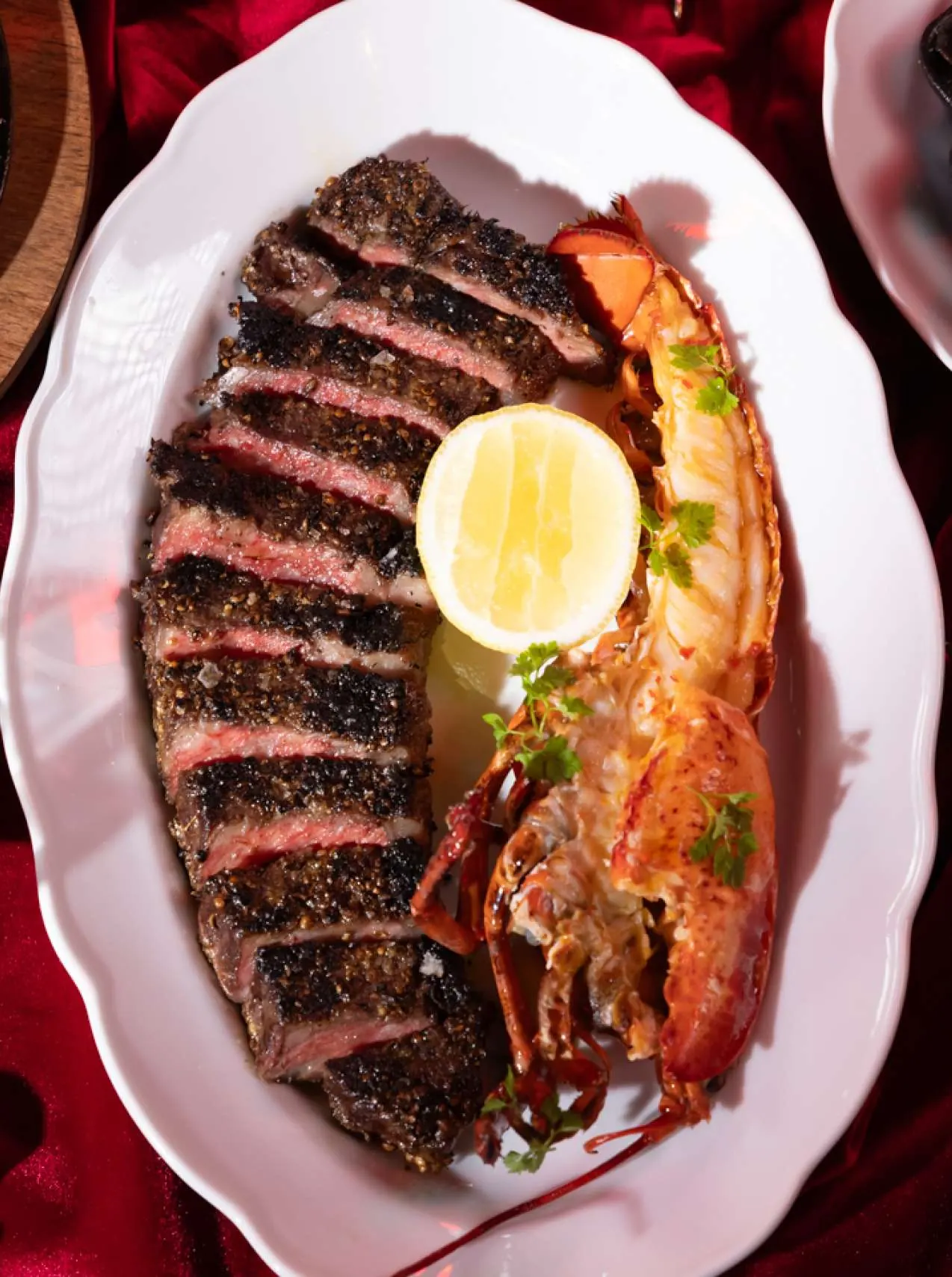 Sliced prime steak with grilled half lobster and lemon at Maxime’s Toronto