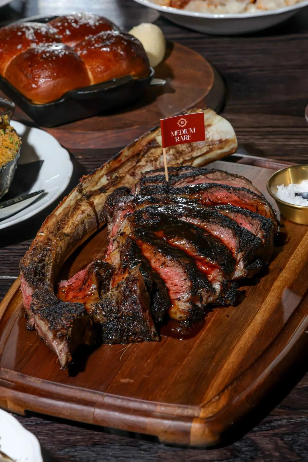 Carved tomahawk steak on a wooden board with house bread